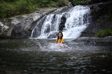 Women enjoying playing in the water at Khlong Nam Lai waterfall in Klong Lan national park, Kamphaeng Phet, Thailand
