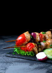 Shashlik made of chicken and vegetables on wooden skewers on the grey table