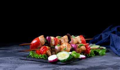 Shashlik made of chicken and vegetables on wooden skewers on the grey table