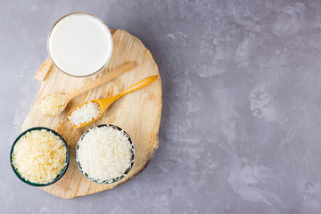 Rice milk and rice seeds on a gray background. Rice milk in glass on a wooden stand. Vegan non-dairy milk on cement background. Alternative milk from rise. Copy space
