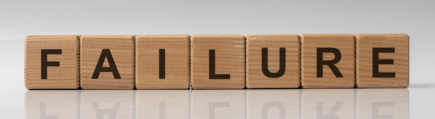 failure word on wooden cube blocks on white glossy background with reflection