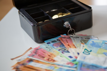 Geldkassette mit Münzen davor Geldscheine