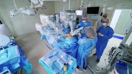 High-tech surgery with robotic equipment. Medical team performing an operation on a patient with a futuristic robot in modern operating theater.
