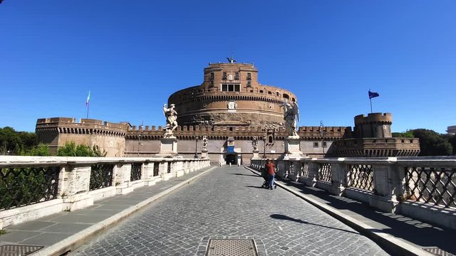a woman taken from behind carries the stroller in front of Castel Sant'Angelo in Rome during the coronavirus pandemic.