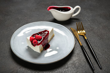 Plate with a piece of cheesecake with jam and raspberries
