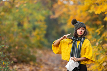 Fototapeta premium teenage girl sneezes in a scarf in the street in autumn. concept of autumn illness or allergy