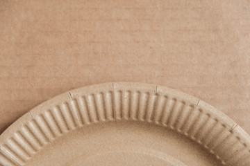 Disposable paper plate on kraft paper background. Eco friendly disposable tableware. Top view. Copy, empty space for text