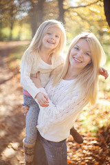 Fototapeta premium Beautiful, happy young mother with little daughter playing in Autumn park.