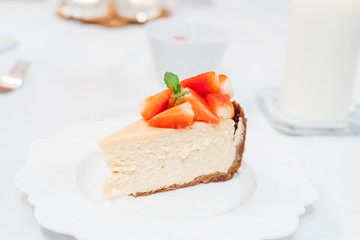 Fresh strawberry cheesecake on a ceramic plate on a white festive table