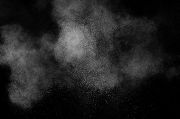 Freeze motion of white particles on black background. Powder explosion. Abstract dust overlay texture.