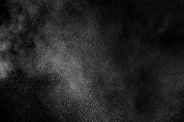 Freeze motion of white particles on black background. Powder explosion. Abstract dust overlay texture.