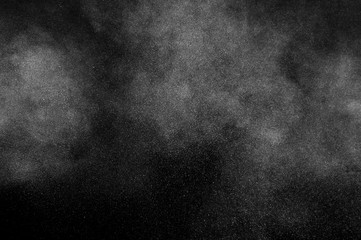 Freeze motion of white particles on black background. Powder explosion. Abstract dust overlay texture.