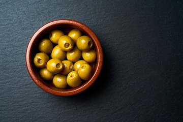 Ceramic bowl with olives on a dark background.