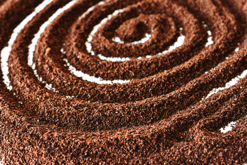 Fototapeta na wymiar A close up image of ground coffee beans form in a swirl on a white background. 