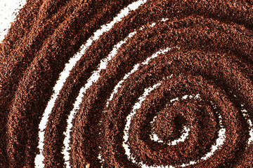 A close up image of ground coffee beans form in a swirl on a white background. 