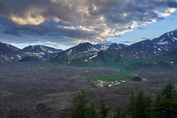 Fototapeta premium Volcanic valley surrounded by mountains with snowy peaks in the evening.