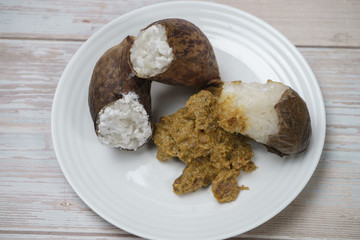 Glutinous rice steamed cooked with coconut milk in pitcher plants known as lemang periuk kera with spicy chicken rendang. A traditional malay cuisine during Hari Raya festival.
