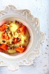 Wheat porridge with pumpkin and pumpkin seeds. Macro photo on a white textured background. Copy of the space.