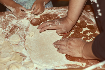 Family concept. Cooking together with children. Little girl leaning how to make manti dumplings. Close up child and grandmother hands