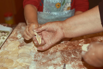 Obraz na płótnie Canvas Family concept. Cooking together with children. Little girl leaning how to make manti dumplings. Close up child and grandmother hands
