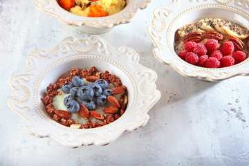 Three different Breakfast cereals in white textured dishes. Copy of the space. Photo on a white textured background. Horizontal photo.