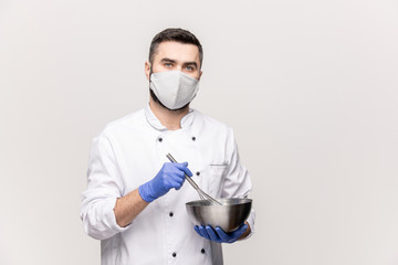 Fototapeta na wymiar Young male chef in uniform, protective mask and gloves mixing milk and raw eggs