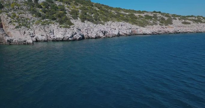 Forward drone shot heading slowly to a rocky shore over the aegean sea, Greece. 4K video quality