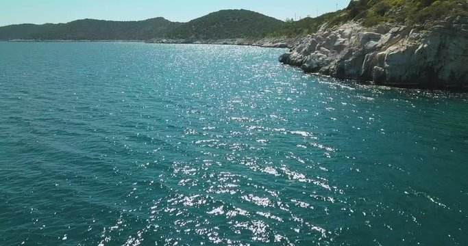 Reveal drone shot next to a rocky shore in the Aegean sea. UHD video quality