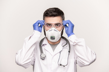 Fototapeta na wymiar Contemporary young doctor in whitecoat, protective gloves and respirator