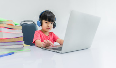 Happy childhood boy wear earphone and enjoy sound and online learning by laptop computer
