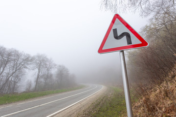 Road sign mountain serpentine. Mountain road in the fog