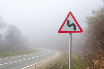Road sign mountain serpentine. Mountain road in the fog