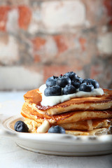 Macro photo of pancakes with blueberries on a white textured plate. Back brick background. Copy of the space.