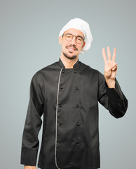 Young chef making a number three gesture