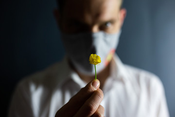 The man in the mask "Stop Coronavirus" sniffs the smell of a fresh flower, COVID-19