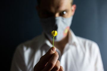 The man in the mask "Stop Coronavirus" sniffs the smell of a fresh flower, COVID-19