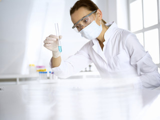 Female laboratory assistant analyzing test tube with blue liquid. Medicine, health care and researching concept