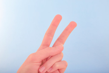 Victory sign and symbol of peace in form of two fingers on light blue background.Close up.Soft focus.Сoncept of success,a good mood,overcoming difficulties.