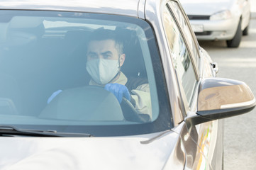Young serious courier in protective mask and gloves driving to clients
