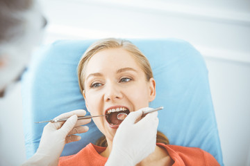 Happy smiling woman is being examined by dentist at dental clinic. Healthy teeth and medicine, stomatology concept