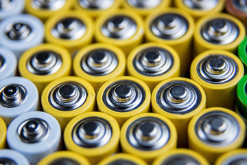 A large number of old AA batteries. The batteries are laid out in a square shape. Batteries form a...