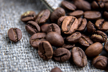 Brown coffee bean close-up.The grains lie on a sacking with a beautiful texture. Macrophotography of coffee. Beautiful grains.