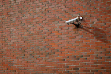 CCTV security surveillance camera mounted on a red brick wall.