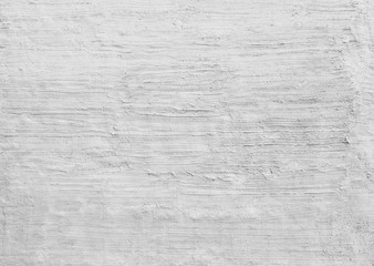 Plastered and rough concrete or stone wall painted in white or light gray, hand made stucco texture. High resolution full frame textured background in black and white. Copy space.