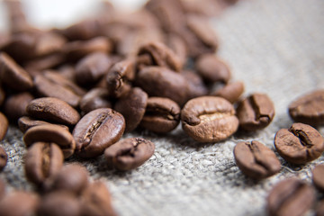 Brown coffee bean close-up.The grains lie on a sacking with a beautiful texture. Macrophotography of coffee. Beautiful grains.