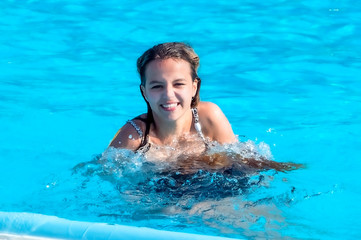 two happy teenager girls playing in the swimming pool at the day time