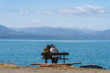 A couple sits on a bench by scenic General Carrera Lake near Puerto Rio Tranquilo in Chile, Patagonia, South America.