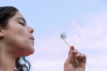 young woman blowing a dandelion.