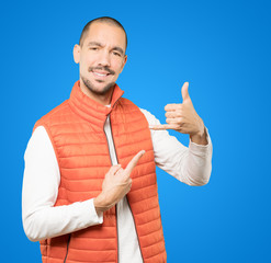 Amazed young man making a gesture of calling with the hand