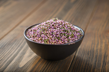 Obraz na płótnie Canvas Black bowl of dry healthy heather flowers on wooden table.
